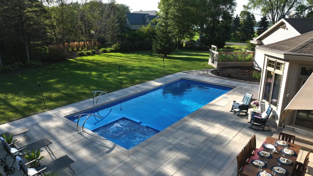 Fiberglass pool and spa overlooking a landscaped backyard lawn in Neenah, Wisconsin