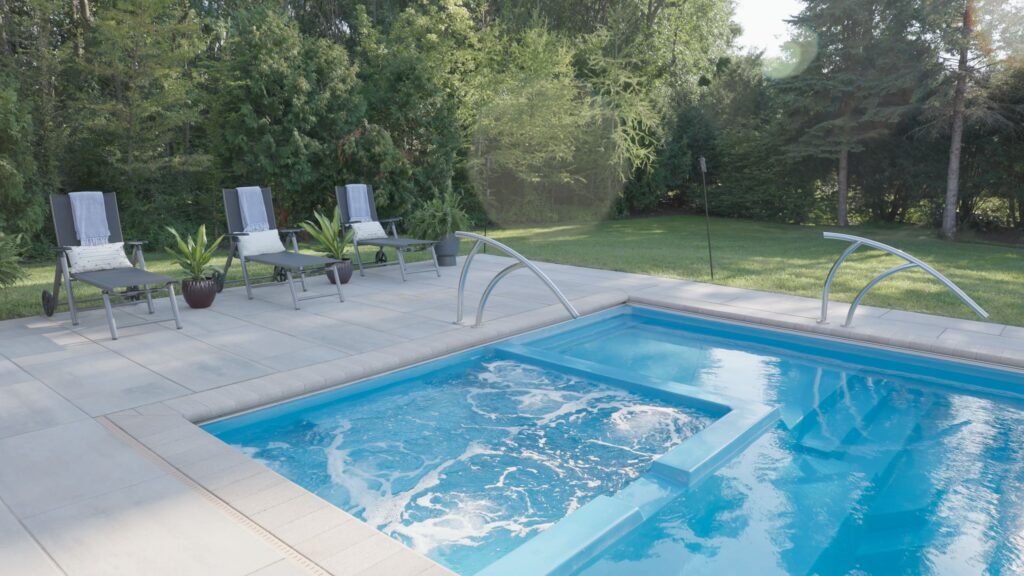 Spa jets running on a fiberglass pool with poolside lounge chairs