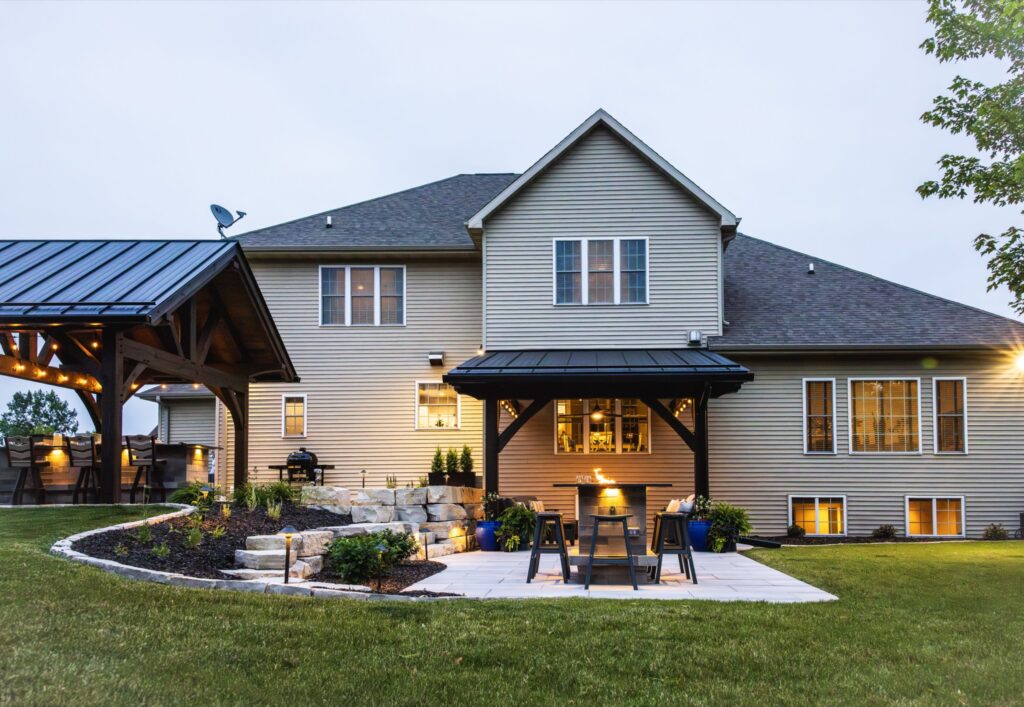 Rear elevation at dusk of a Neenah home with a timber pavilion and covered patio