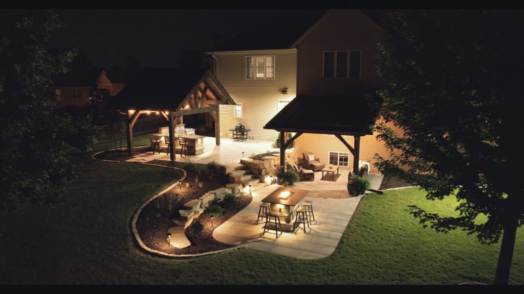 Night view of a Neenah backyard with a lit pavilion, outdoor bar and landscape lighting