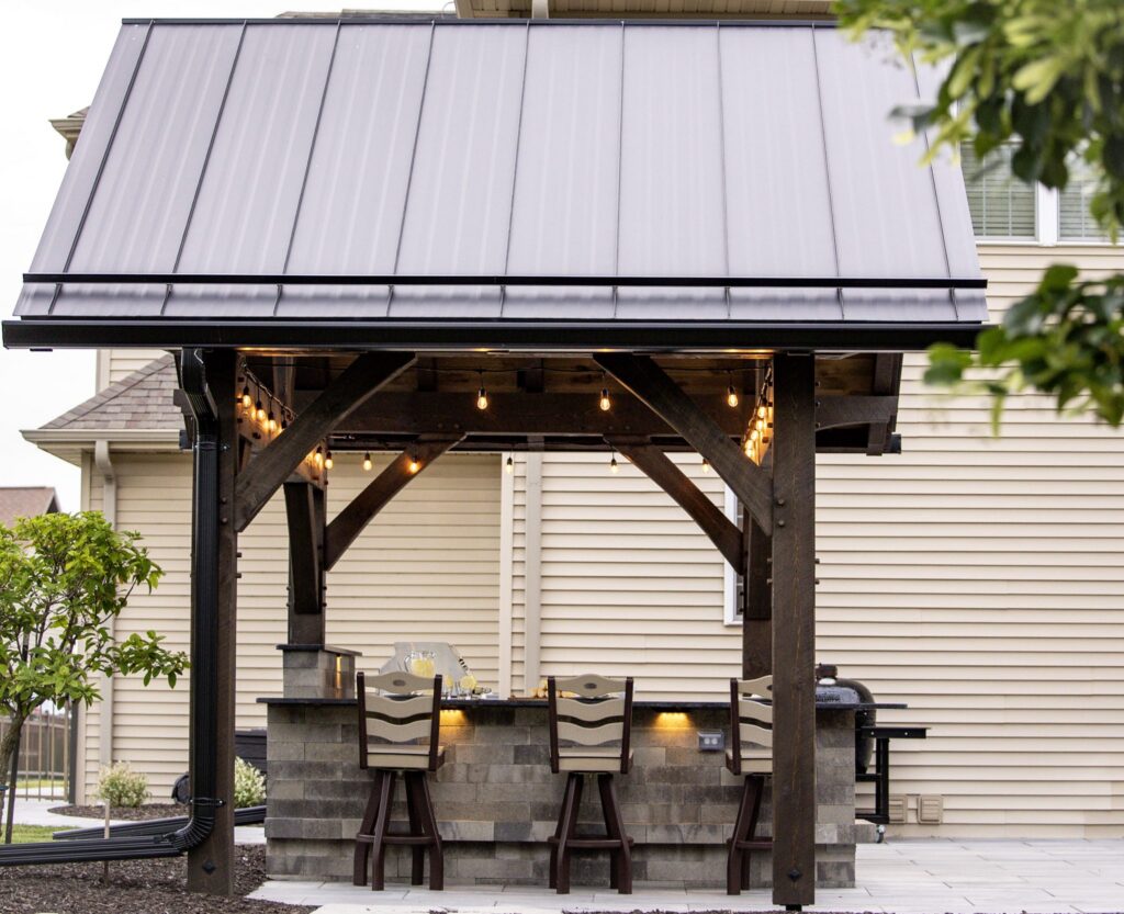 Timber pavilion with cafe lights over a stone outdoor bar and swivel stools