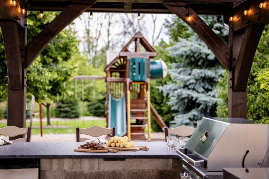 Outdoor kitchen counter under the pavilion looking out to the backyard playset