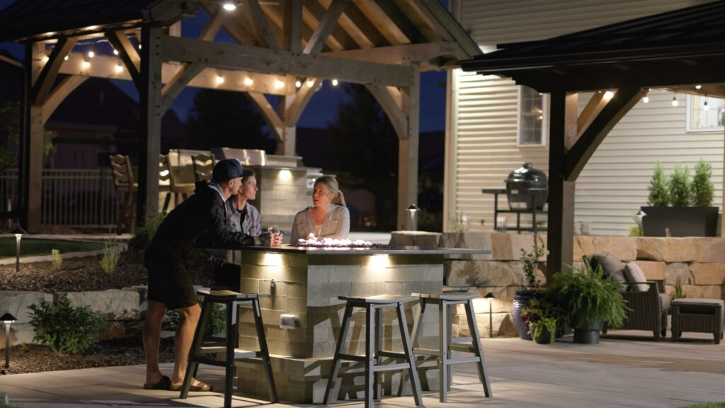 Guests gathered at the lit outdoor bar under the pavilion at night