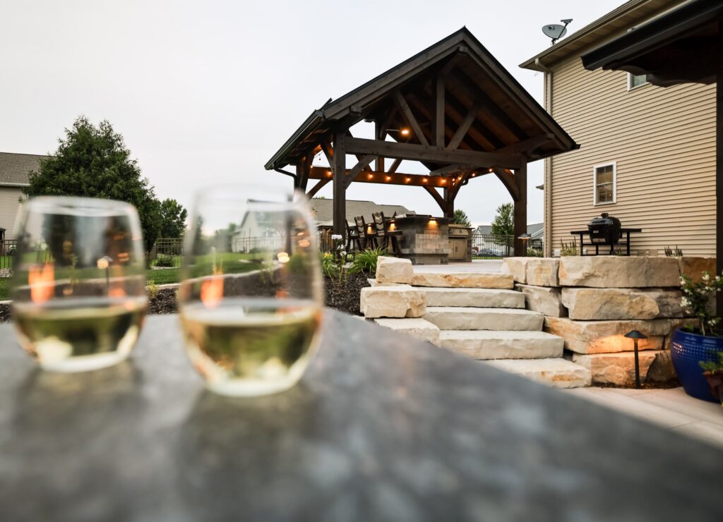 Wine glasses on the bar top with the timber pavilion and stone steps beyond
