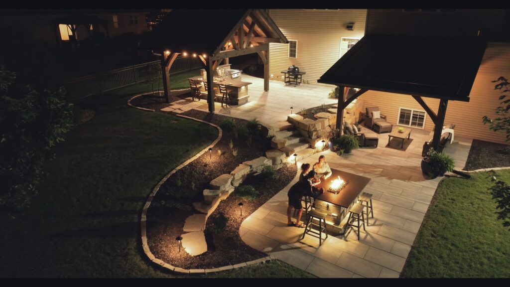 Night aerial of the lit pavilion, paver patio and landscape lighting