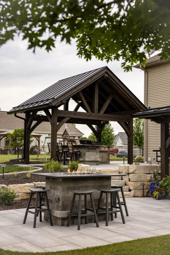 Timber pavilion and stone outdoor bar seen from the paver patio