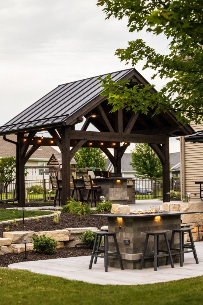 Timber pavilion and stone bar with landscaped beds and boulder edging