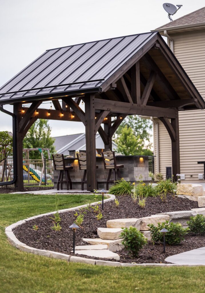 Timber pavilion beside a curved paver walkway and landscaped beds