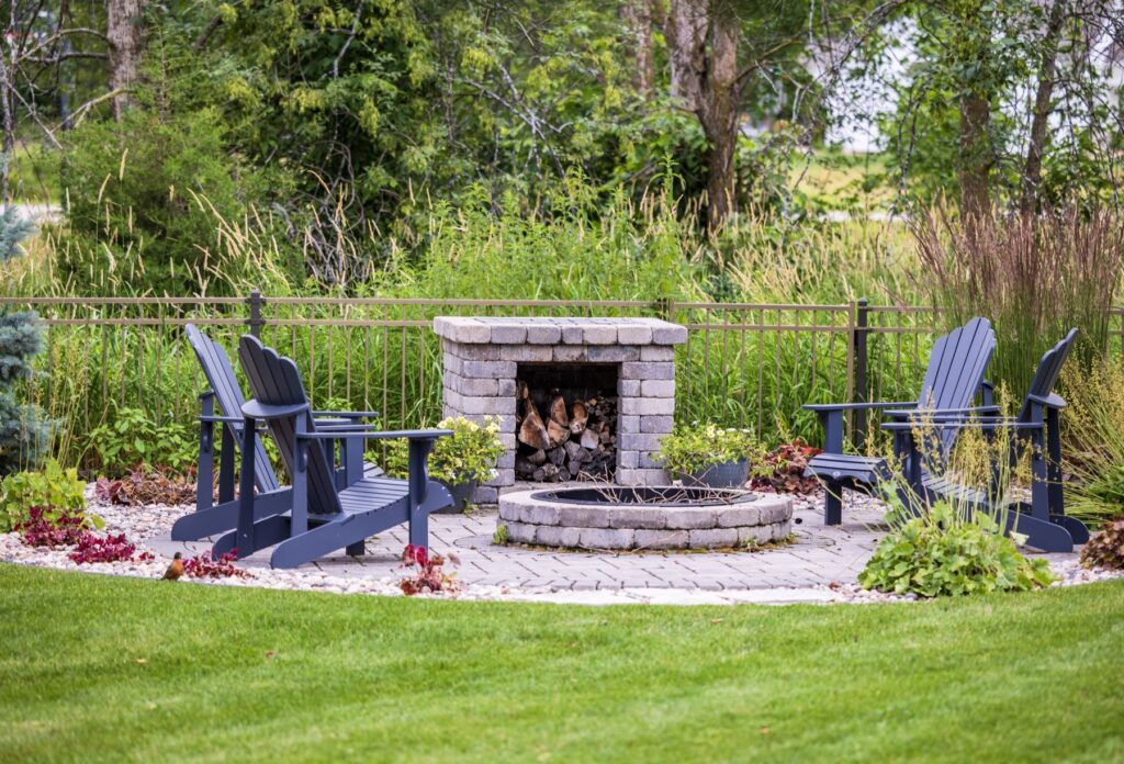 Masonry outdoor fireplace and paver seating area framed by ornamental grasses