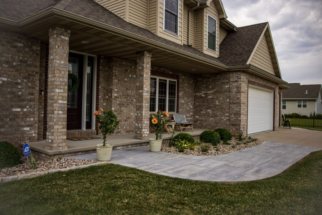 Paver walkway leading to the covered front entry of a brick home