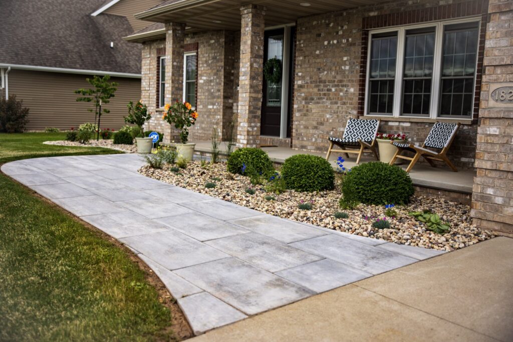 Paver walkway and landscaped beds along the front of a brick home